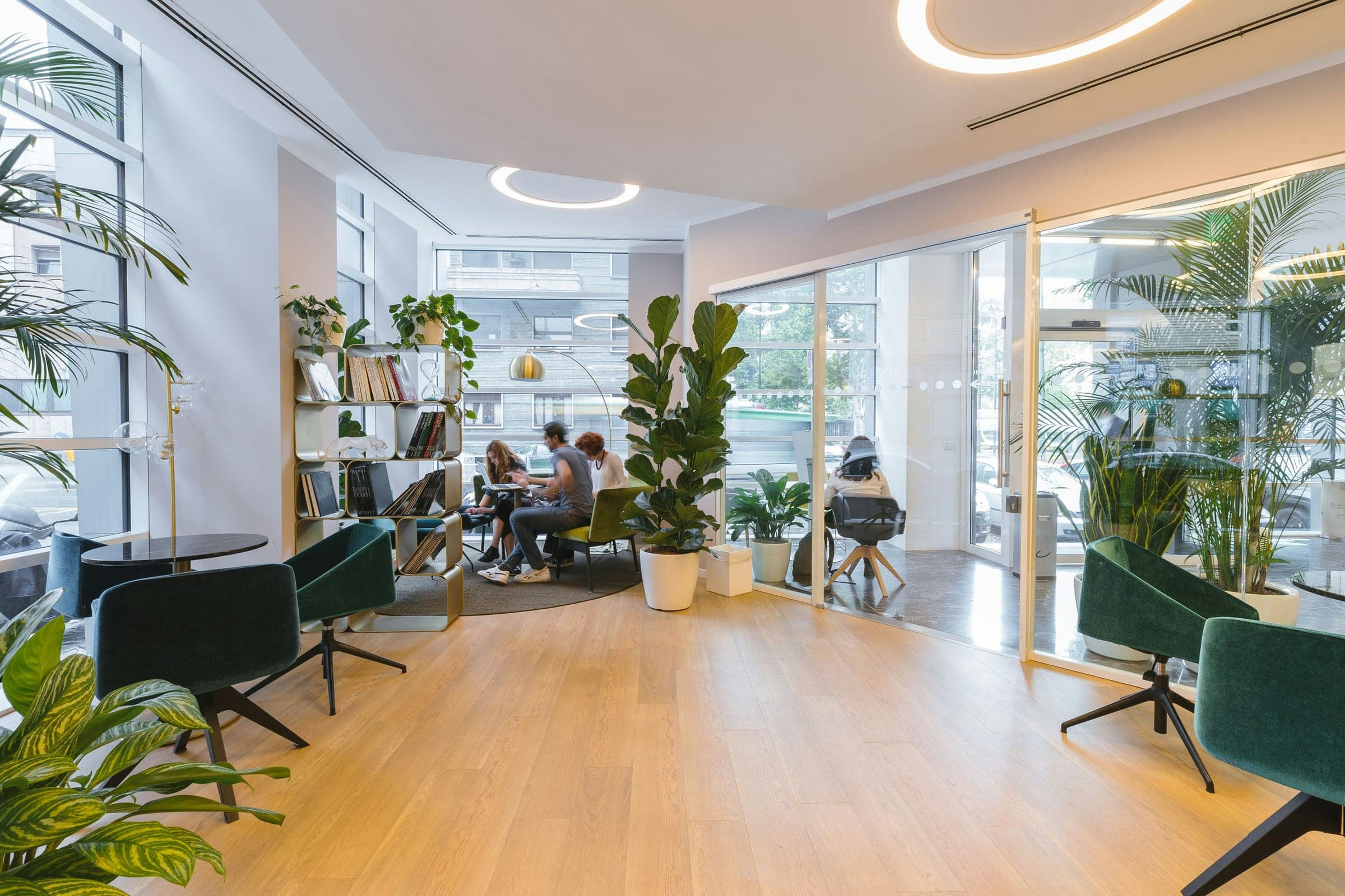 Salle de réunion lumineuse dans un bâtiment tertiaire : grandes baies vitrées, plafond technique à gaines apparentes, table en bois et fauteuils, environnement représentatif des espaces que Victeon pilote.